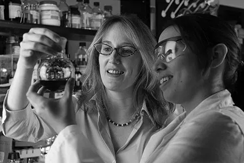 two faculty holding a cylinder.