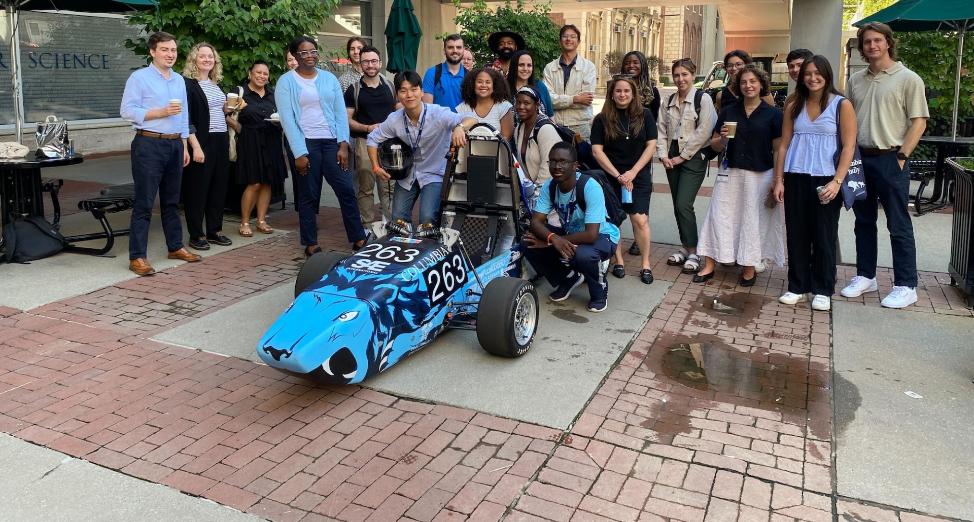 Columbia Engineering staff and Formula Racing team members posing for a photo with their race car outside the Mudd building