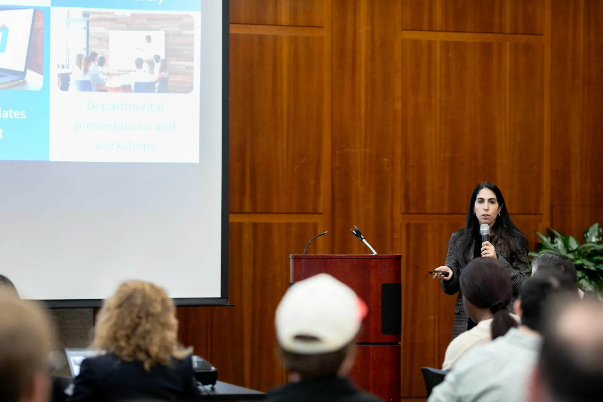 A speaker holding a microphone addresses an audience.