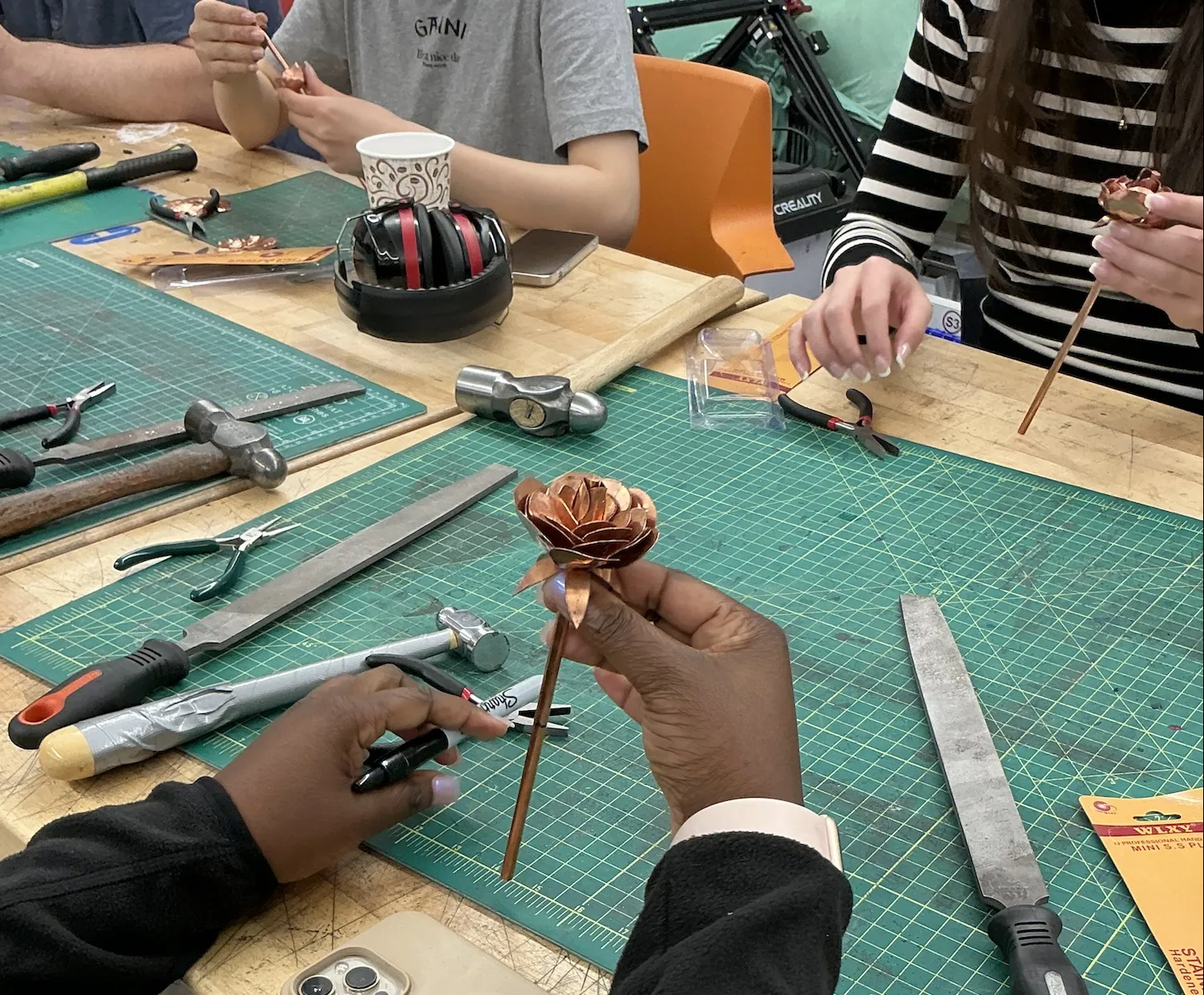A copper rose held in someone's right hand.