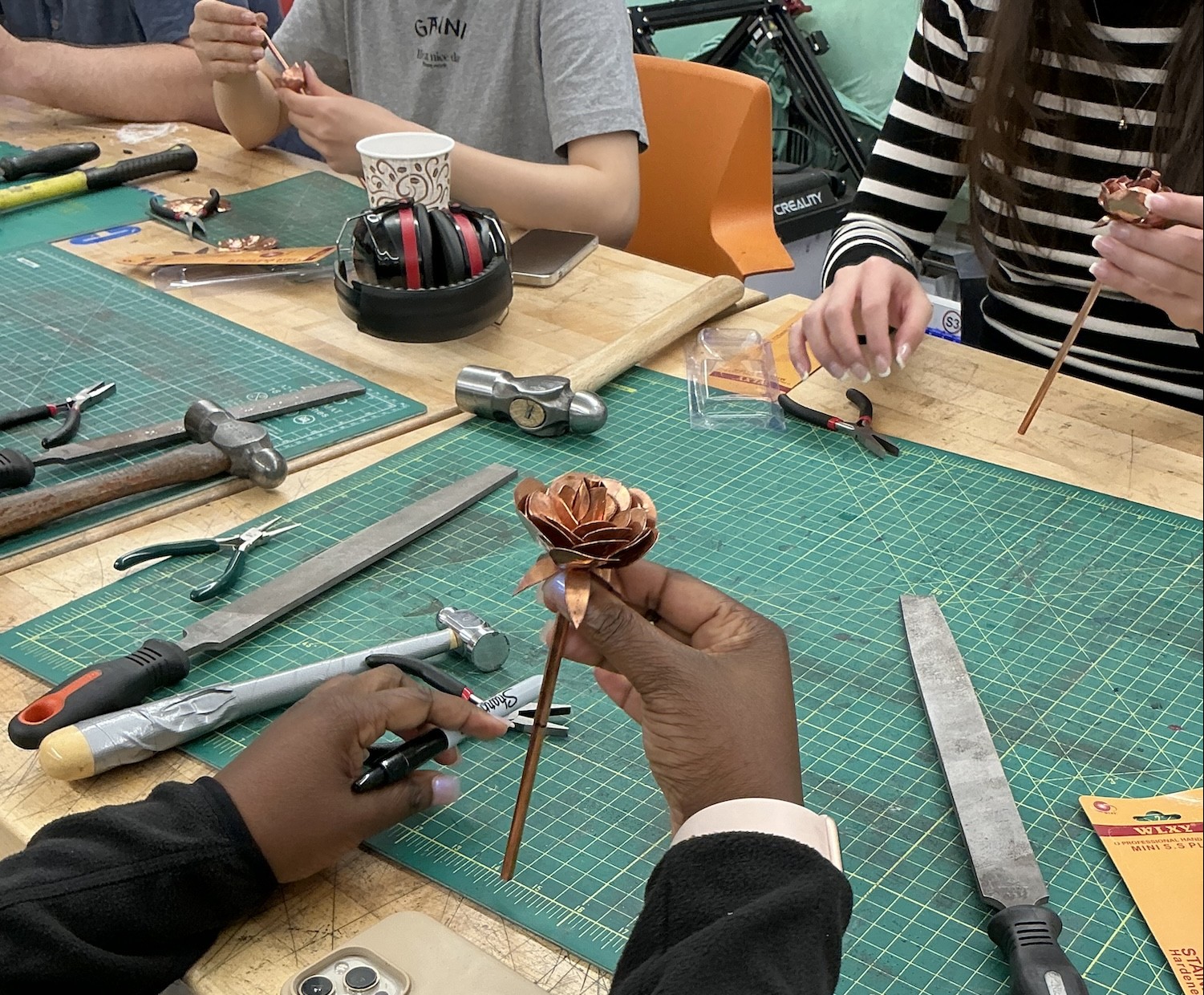 A copper rose held in someone's right hand.