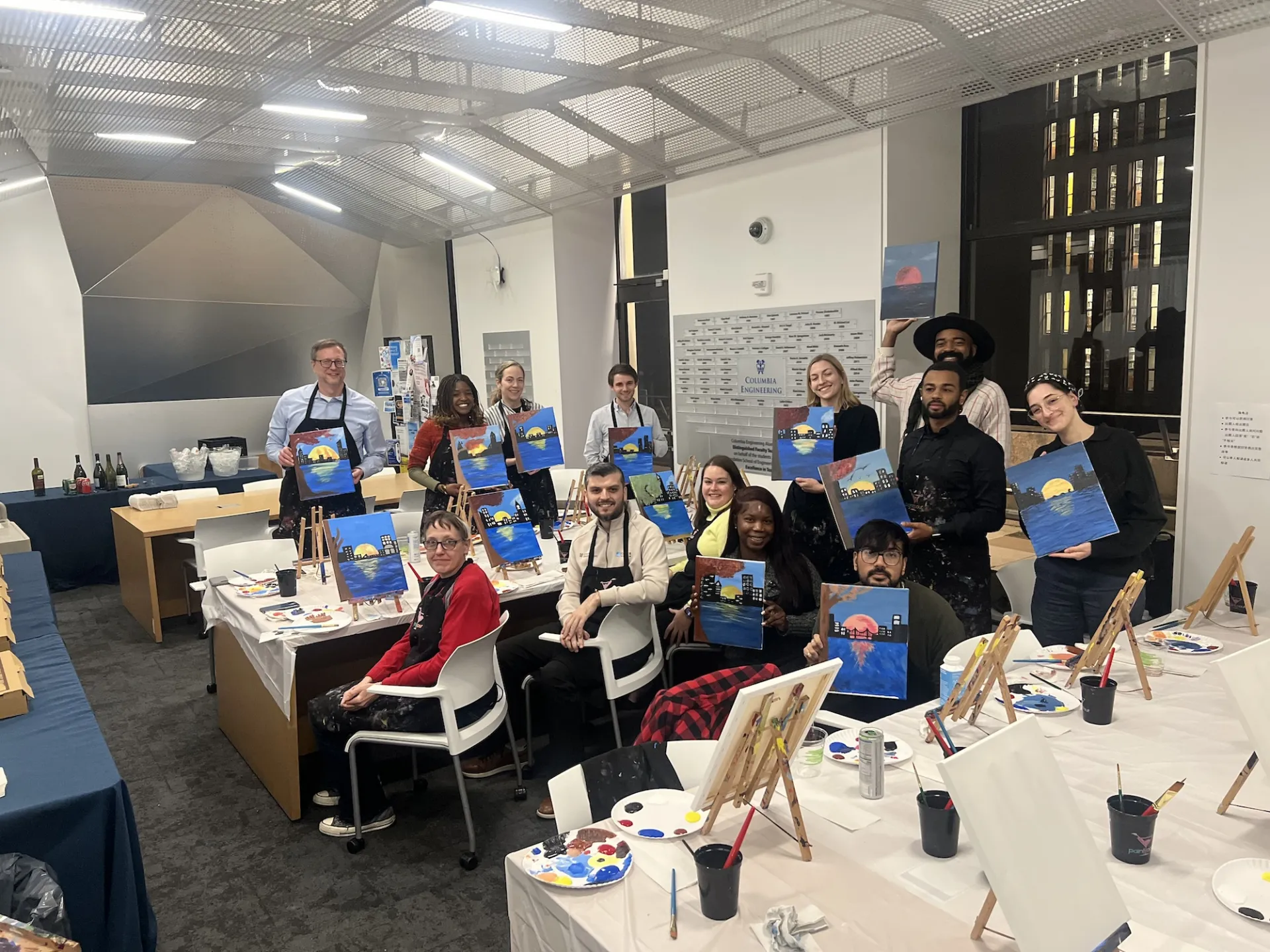 13 Columbia Engineering staff members smiling with their finished paintings