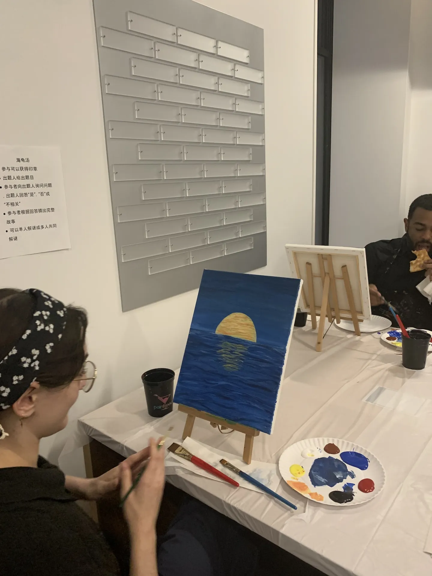 A Columbia Engineering staff member looks at their painting of the moon's reflection in water