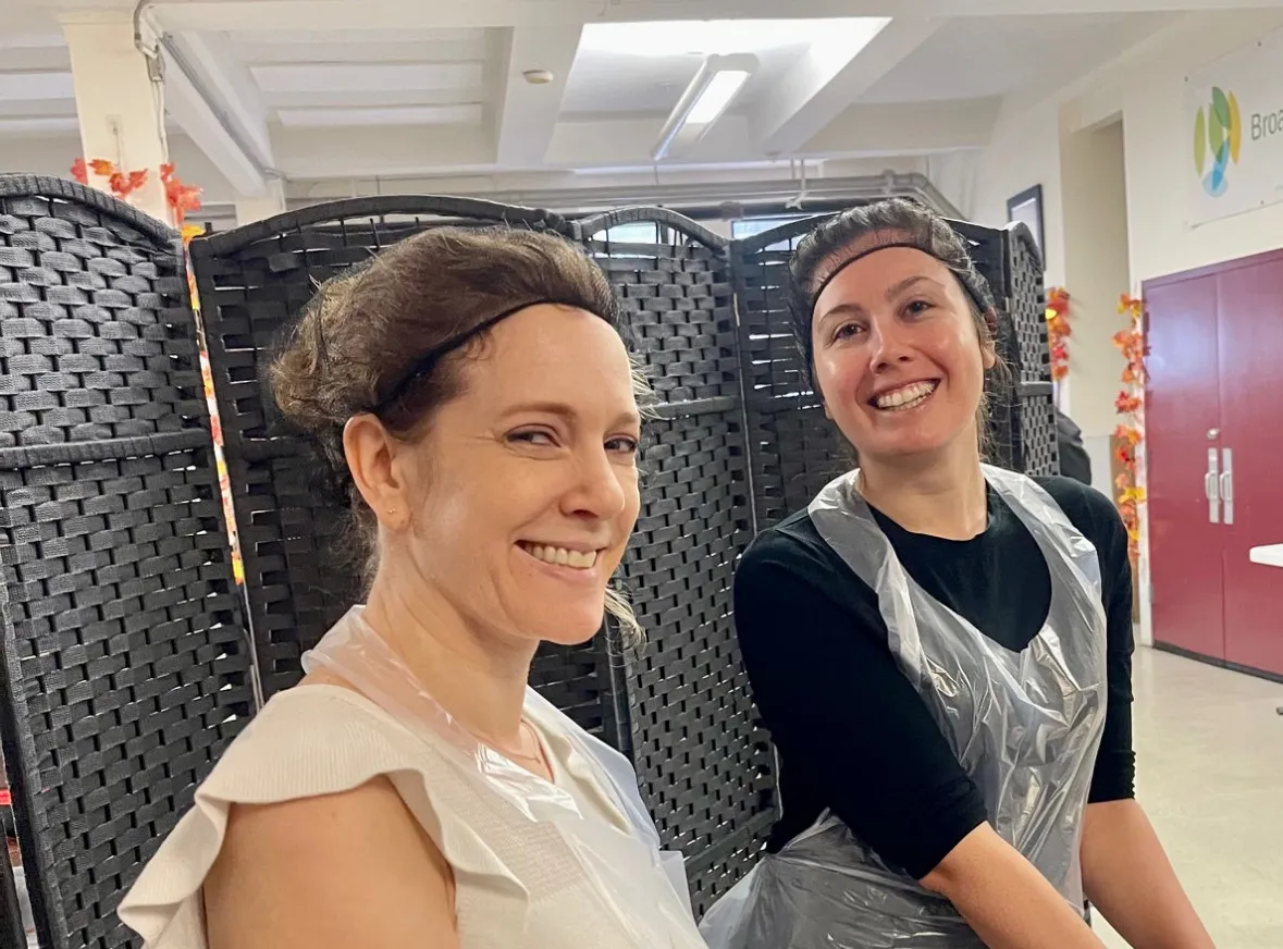 two staff members posing and smiling while volunteering 