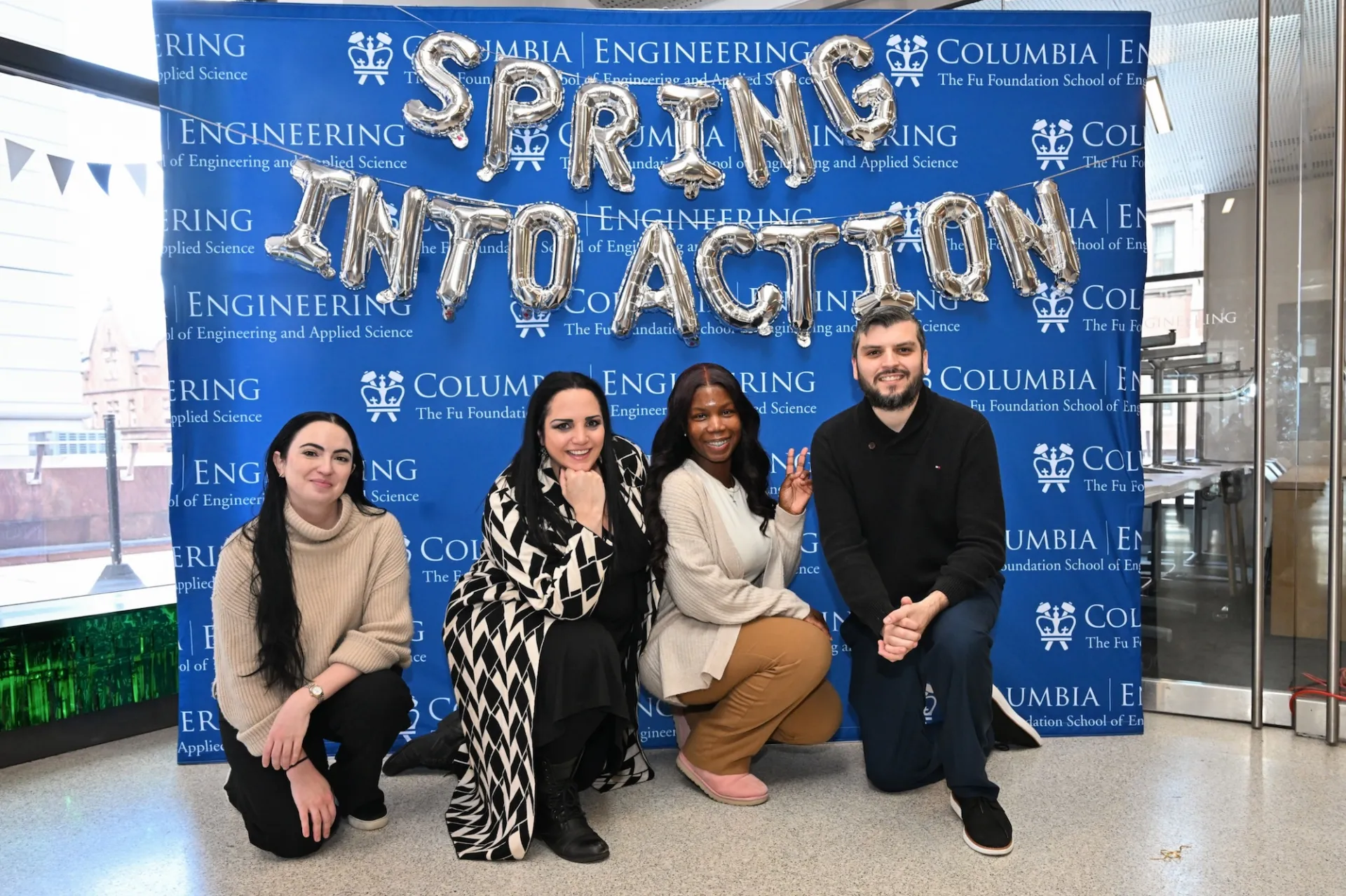 Four Columbia Engineering staff posing in front of balloons that read "Spring into Action"