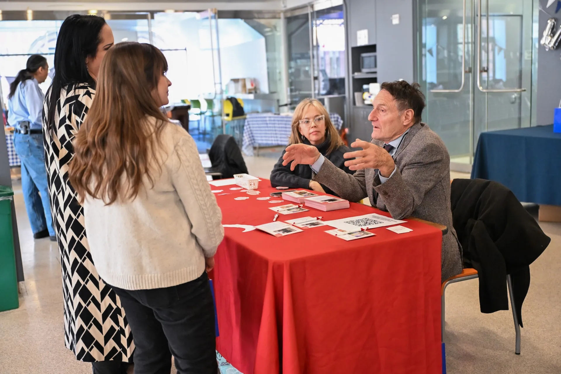 Two people standing next to two people sitting at a table