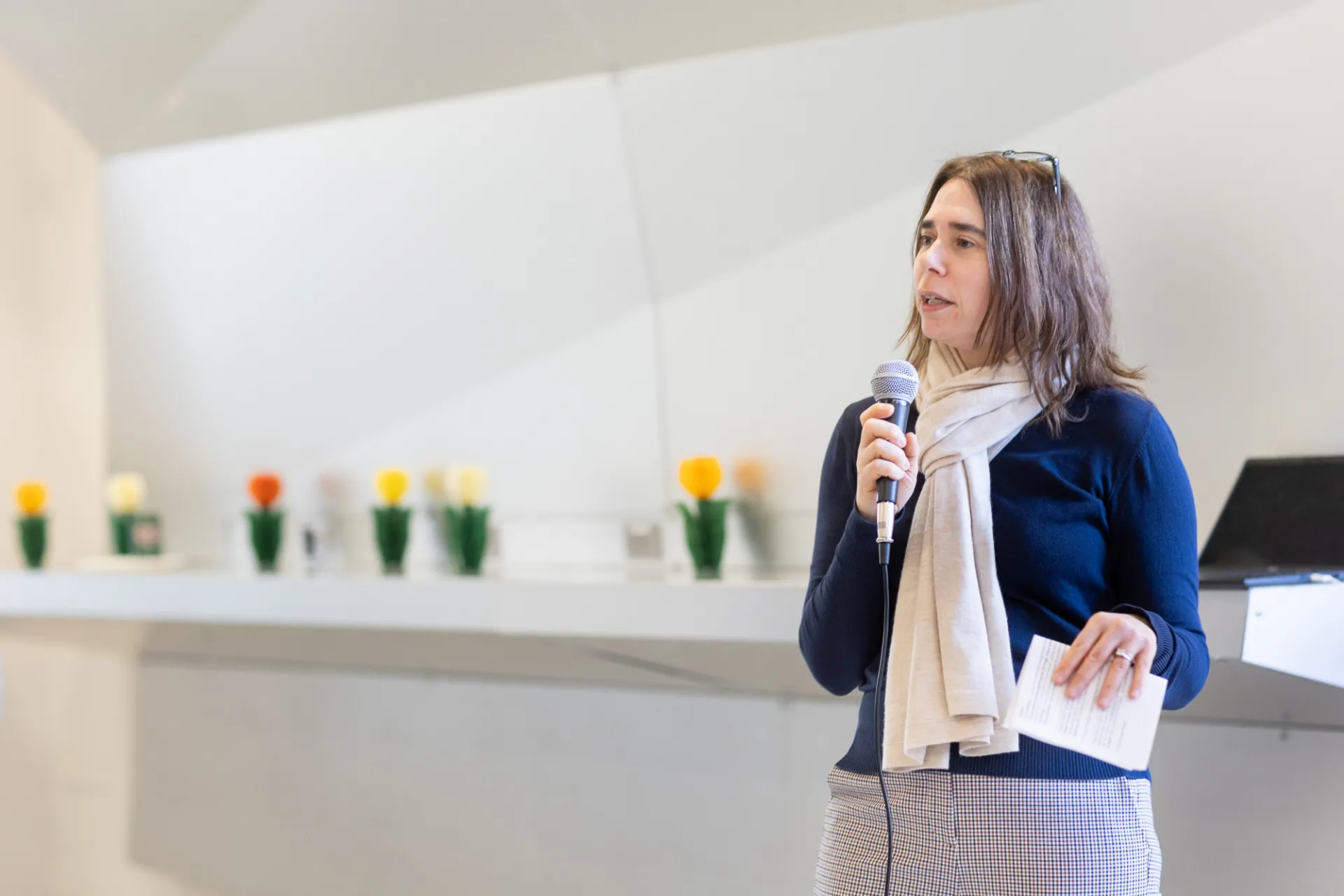 Another executive speaking into a microphone with flowers behind her