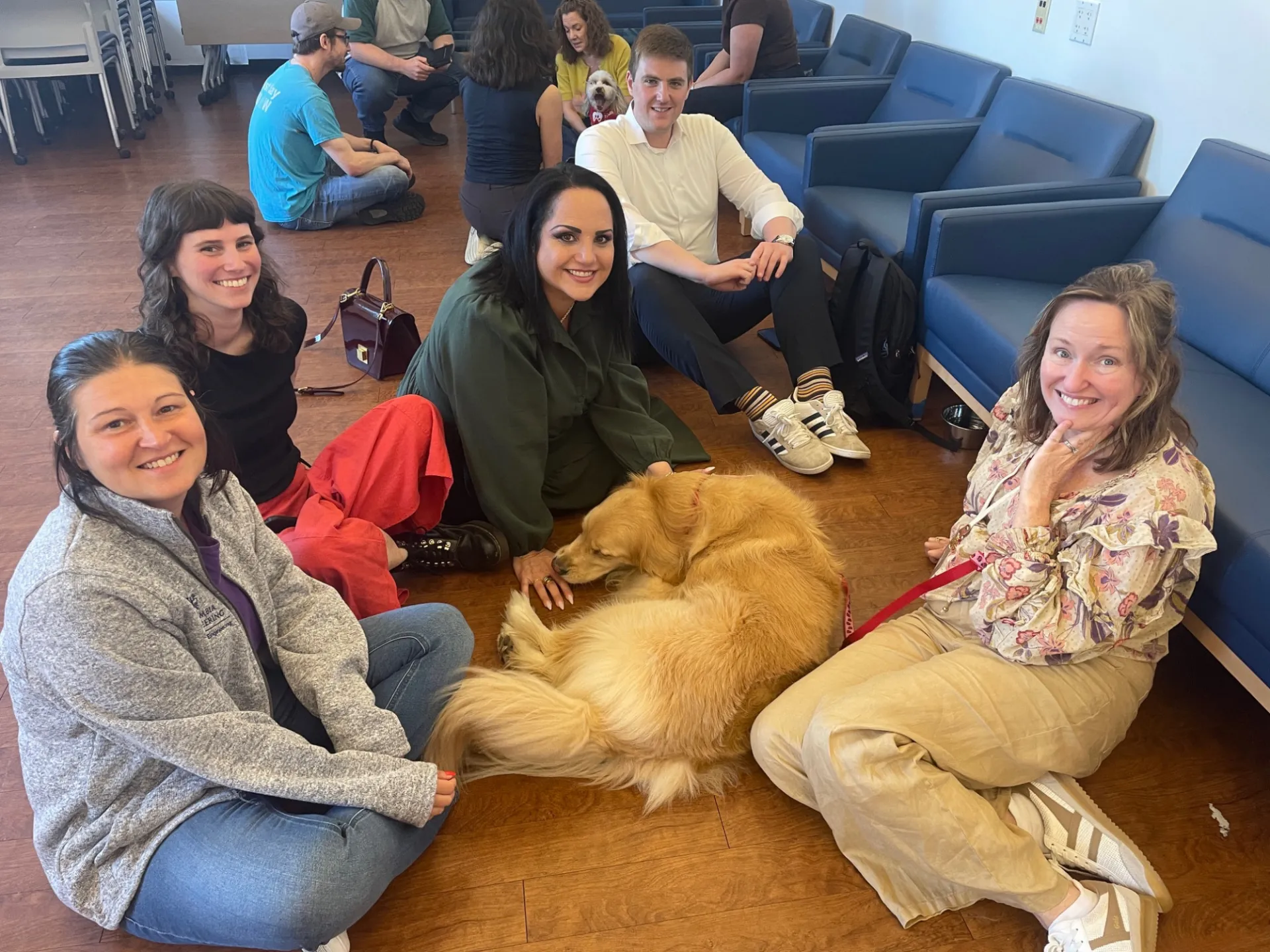 Five people seated while posing with golden retriever 