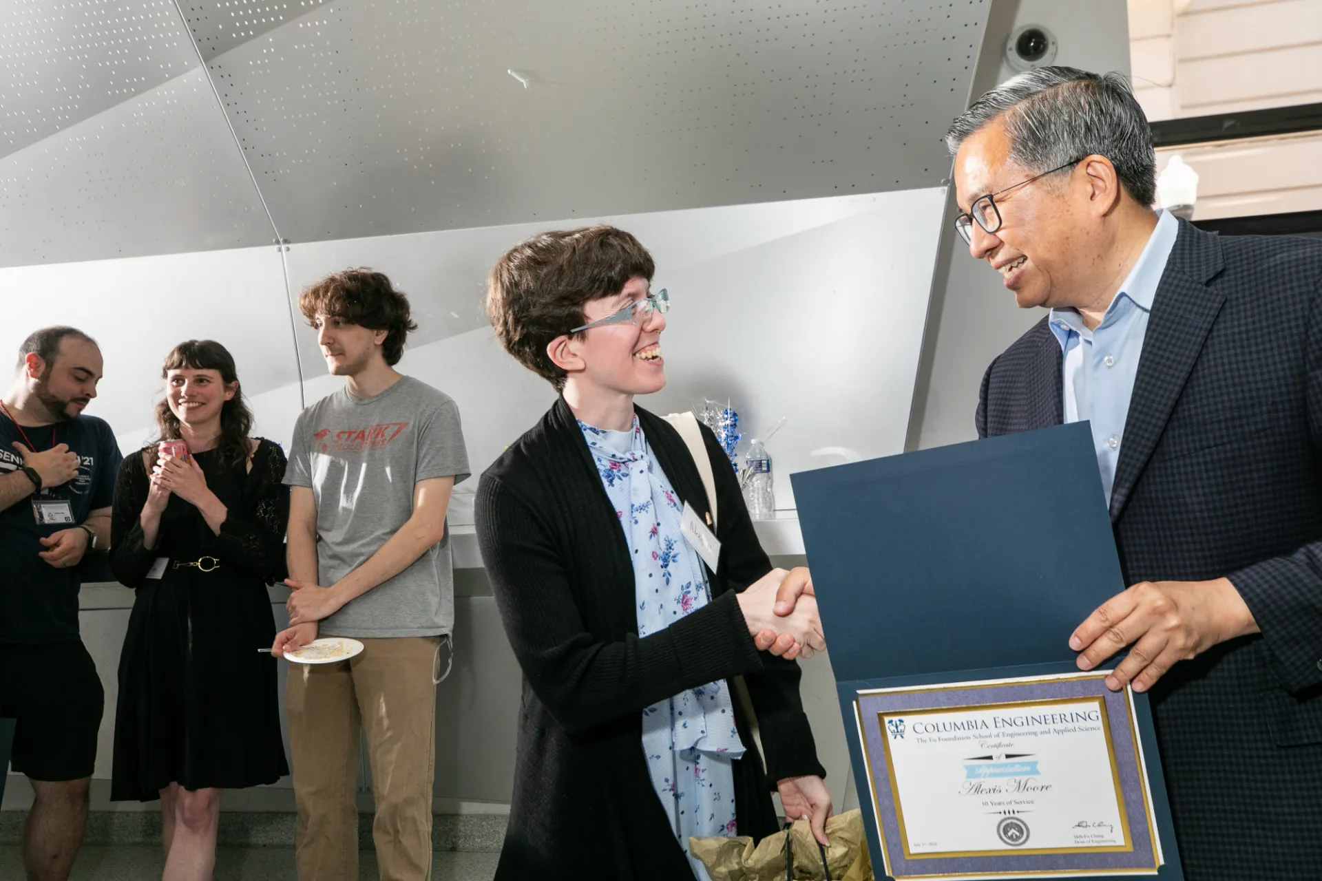 Dean shaking hands with staff member while presenting certificate 
