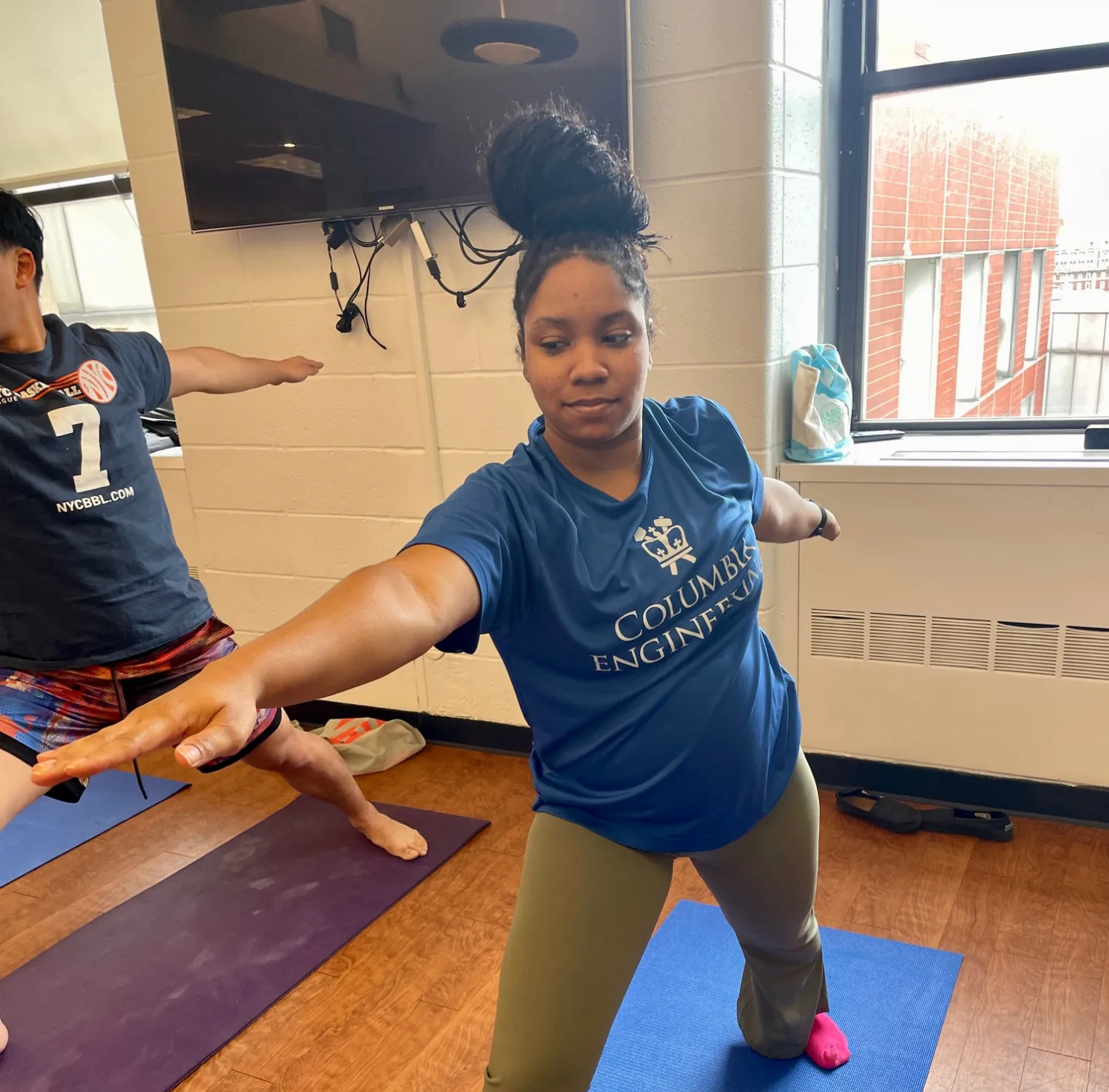 A staff member wearing a columbia engineering t shirt doing a warrior pose