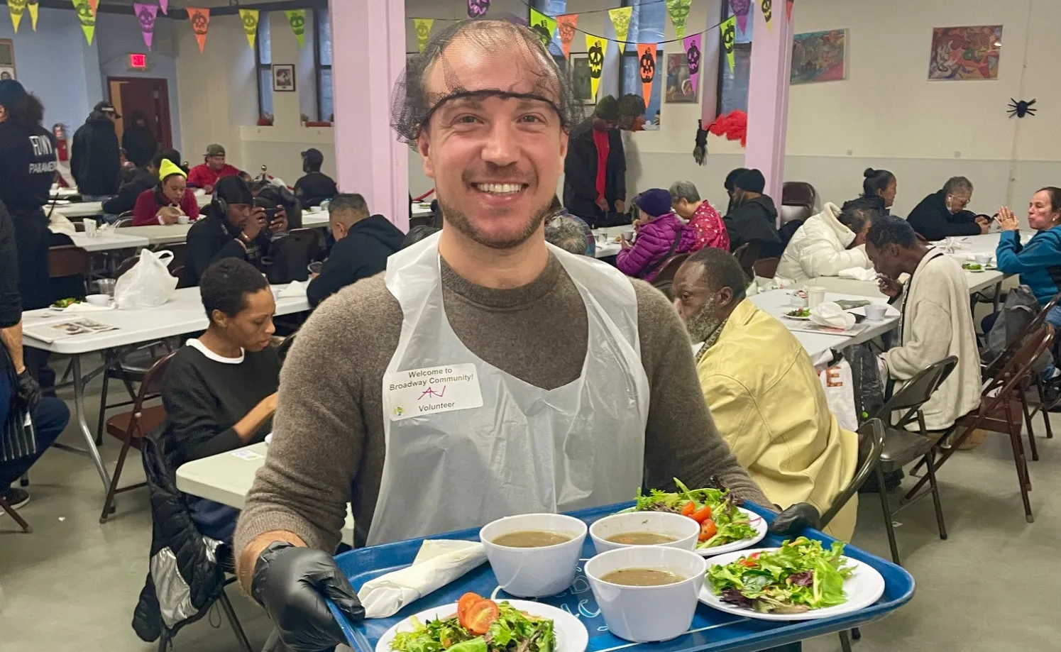 A staff member holding soup and salad to be served 