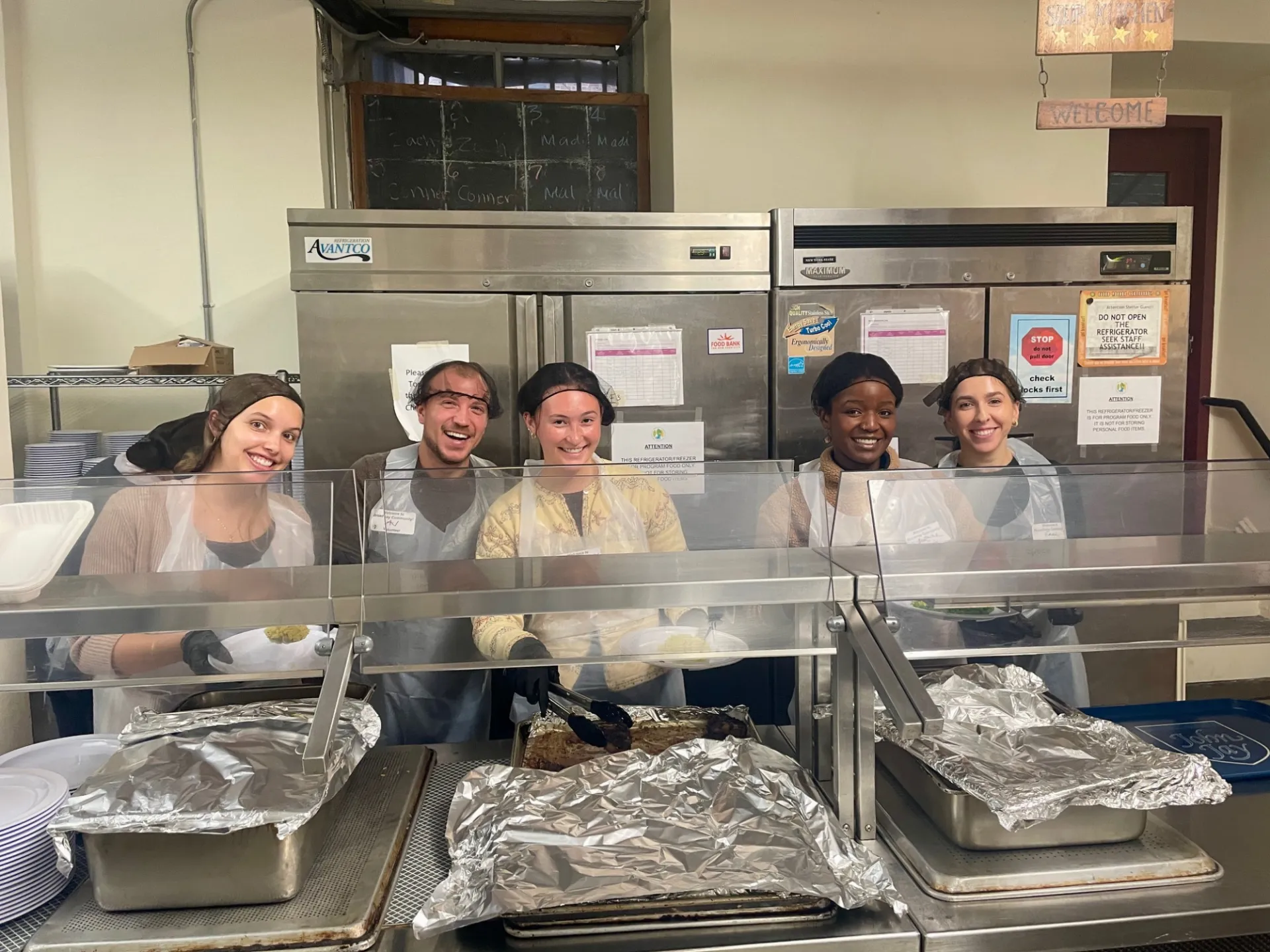 Columbia engineering staff preparing meals to be served while smiling