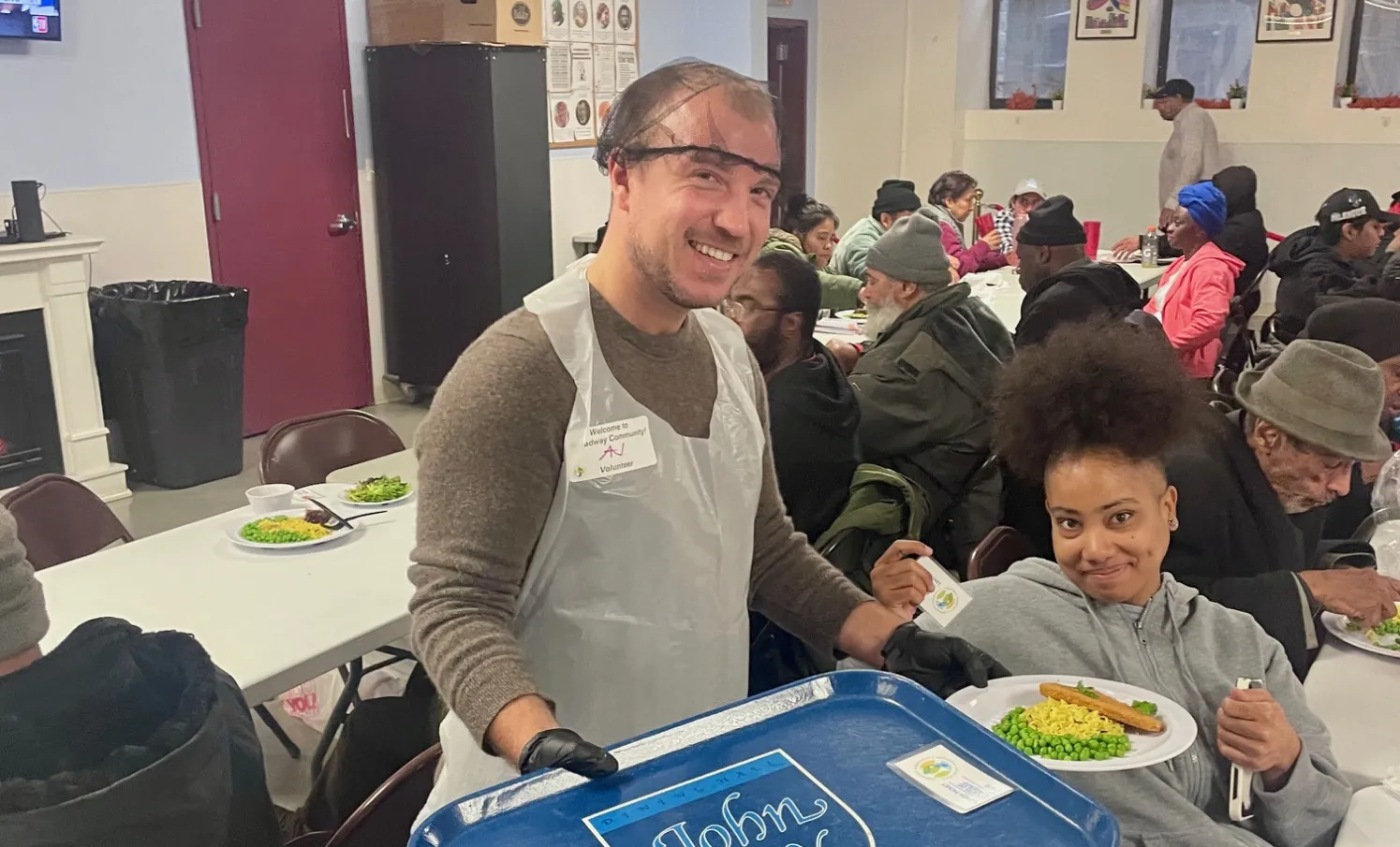A staff member serving a member of the community food and both are smiling