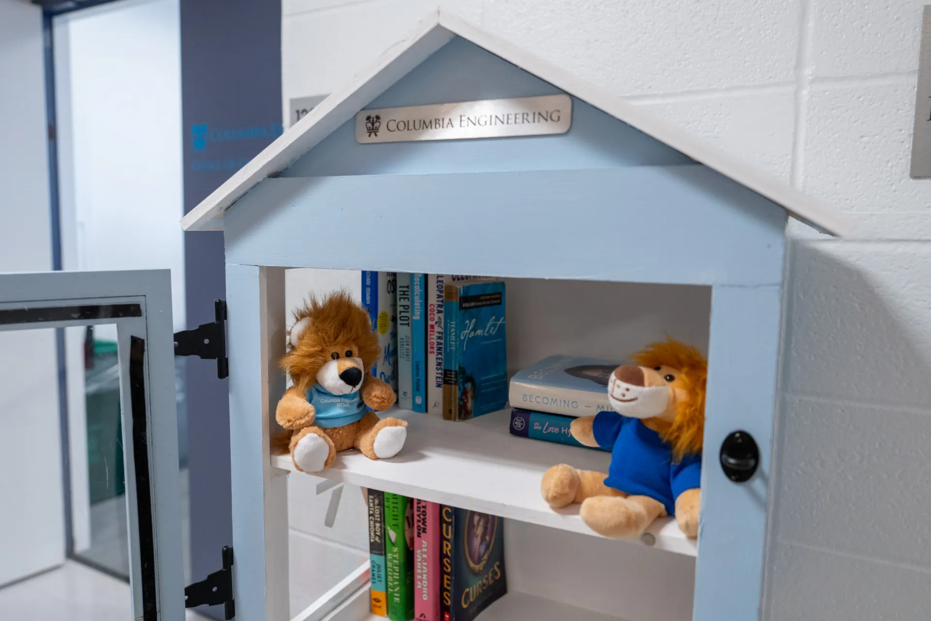 Some books and stuffed animals inside little library